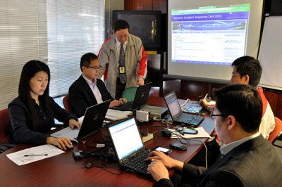 Mr Roy Ko, Principal Consultant (IT Industry Development) of HKPC and Manager of HKCERT, (standing) monitored the drill at the command centre with representatives of Hong Kong Police and the Office of the Government Chief Information Office